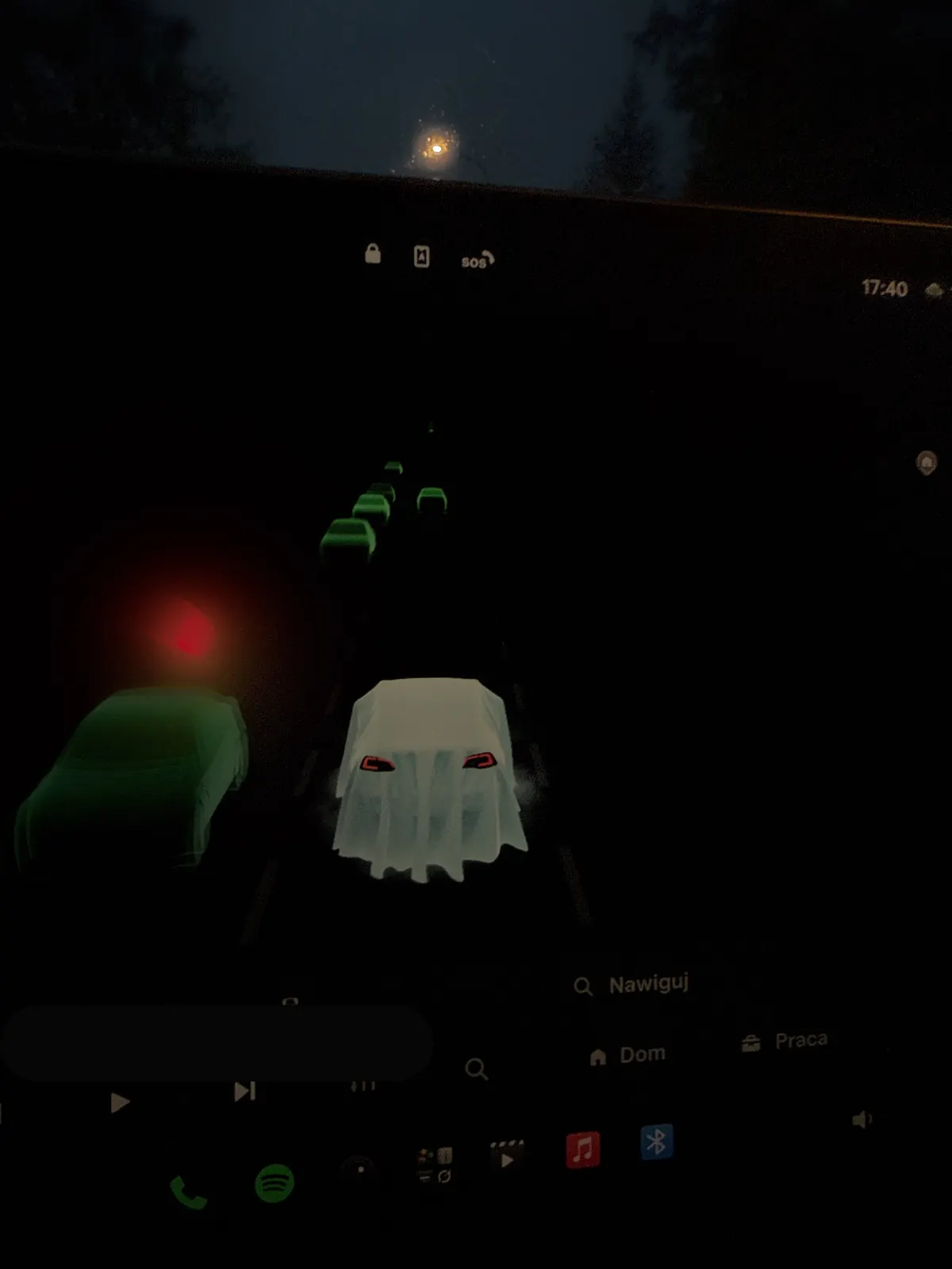 Tesla Halloween Mode driving view: the car as a sheet-covered ghost among green-tinted traffic